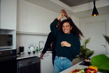 Mixed race couple having fun in the kitchen. Mixed race couple dancing together. High quality photo