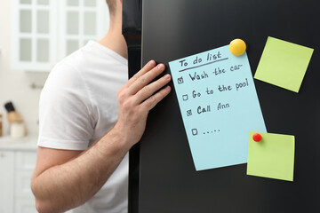Man near refrigerator with to do list on door in kitchen, closeup