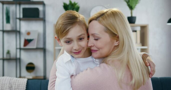 Happy mothers day where adorable in high spirits loving mother hugging and kissing her handsome joyful 12-aged son ,front view