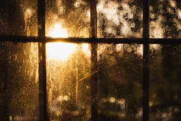 the light of the setting sun after the rain through the wet glass with a grate