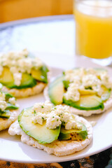 Breakfast of puffed wheat toast with avocado and fresh cheese.