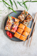 Assortment of sushi rolls served with ginger, sticks on ceramic plate. Sushi menu. Japanese food.