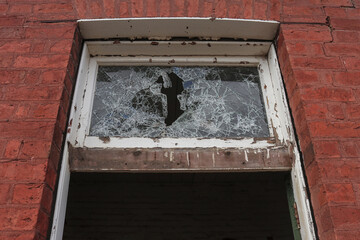 vandalised broken glass window in a derelict industrial building