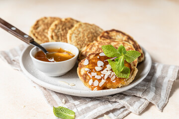 Healthy oat pancakes with jam, nuts and mint on ceramic plate. Vegan breakfast food.