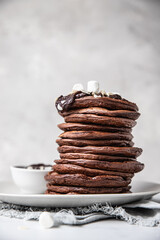 Chocolate pancakes with melted chocolate, ground almond and marshmallow, light background.