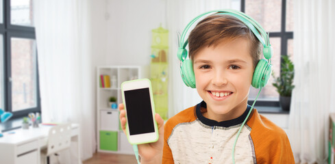 leisure, technology and people concept - happy smiling boy in headphones listening to music and...
