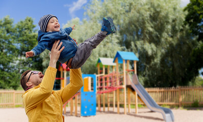 family, childhood, fatherhood, leisure and people concept - happy father and little son playing and having fun over children's playground background