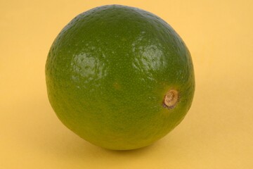 Citron vert en gros plan sur fond jaune