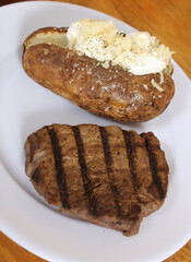 Sirloin Steak With Baked Potato and fresh rolls in background Shallow DOF Focus on Steak