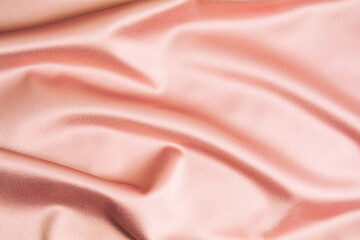 Textured backdrop of pink silk or satin. Shiny waves of textiles. Copy space