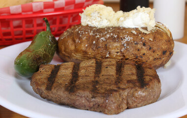 Sirloin Steak With Baked Potato and fresh rolls in background Shallow DOF Focus on Steak