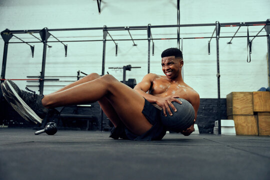 African American male doing an intense workout in the gym. Male athlete doing sit-ups with medicine ball. High quality photo