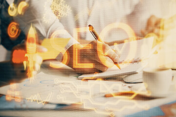 Double exposure of SEO drawing over people taking notes background. Concept of search optimization