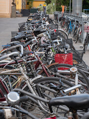 Many old Bicycles Padlocked to the Rack near Train Station