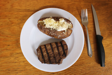 Sirloin Steak With Baked Potato and fresh rolls in background Shallow DOF Focus on Steak