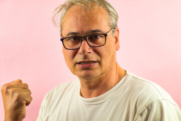 closeup of mature man with raised fist celebrating on pink background