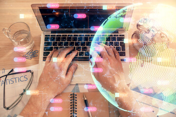 Multi exposure of man's hands typing over computer keyboard and world map hologram drawing. Top view. Technology concept.