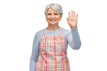 Obraz premium cooking, culinary and old people concept - portrait of smiling senior woman in kitchen apron waving hand over white background