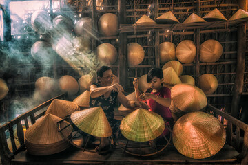 Vietnamese Old woman craftsman teaching the grandchild making the traditional vietnam hat in the old traditional house in Ap Thoi Phuoc village, Hochiminh city, Vietnam, traditional artist concept - 440236563