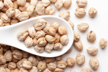 Macro Close-up of Organic chhole chana or Kabuli chana (Cicer arietinum) or whole white Bengal gram dal on a white ceramic soup spoon. Top view, over gradient background of itself.