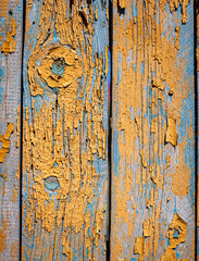 Wood texture with yellow flaked paint. Peeling paint on weathered wood. Old cracked paint pattern on rusty background. Chapped paint on an old wooden surface