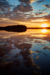 Obraz premium Scenic and beautiful sunset and dramatic cloudy sky and their reflections on a calm lake in Finland at summer.