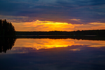 Scenic and beautiful sunset and colorful cloudy sky and their reflections on a lake in Finland at summer.