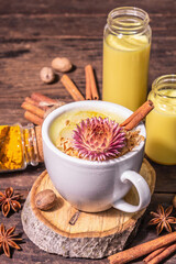 Golden turmeric milk with ice on bright yellow background