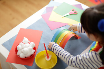 young girl making paper rainbow craft for homeschooling