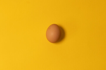 Chicken egg on yellow background. Natural healthy organic food. Top view, flat lay, copy space.