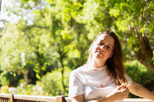 Retrato de una mujer joven bonita tacandose el pelo en un parque