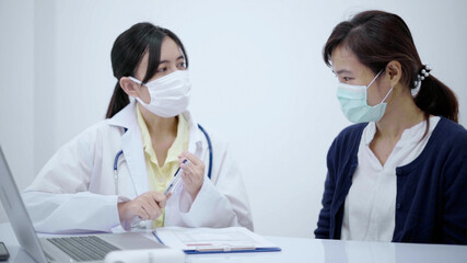 Doctor wearing protective mask consulting patient show X-ray result with digital tablet.