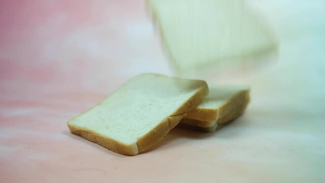 Slices of white bread falling on stock sliced bread. Shot of slow motion