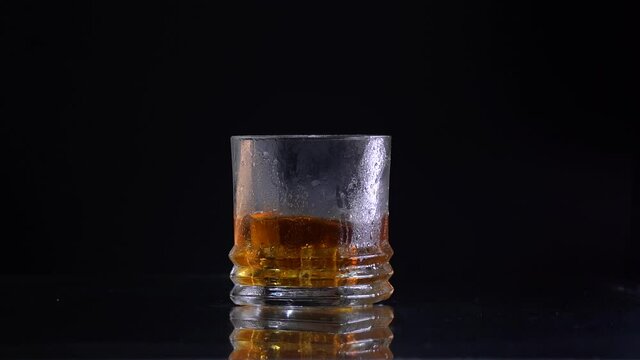 Super Slow Motion Shot of Droping the ice to the glass with Whiskey