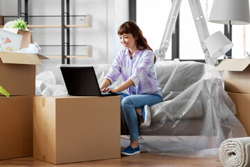 moving, people and real estate concept - happy smiling asian woman with laptop computer and boxes at new home