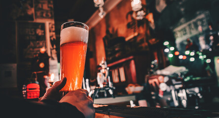 man holds a glass of beer in his hand at the bar or pub