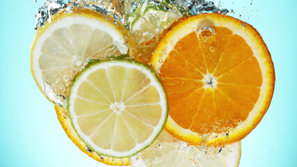 Fototapeta na wymiar Fresh limes, oranges and lemons slices dropped into water with splash