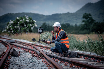 Engineer under inspection and checking construction process railway switch and checking work on railroad station .Engineer wearing safety uniform and safety helmet in work.