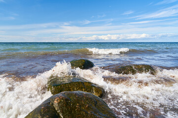 Fototapeta na wymiar Waves break on rocks from the shore by the sea
