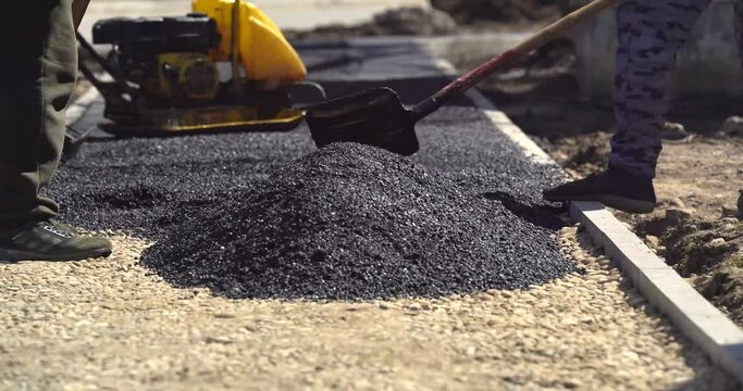 Paving asphalt distributes hot asphalt onto the road while workers spread it out