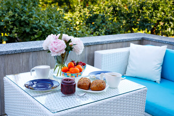 Breakfast table with bread, fresh fruits and strawberries and coffee served on balkony terrace or hotel on summer morning for romantic couple lunch.