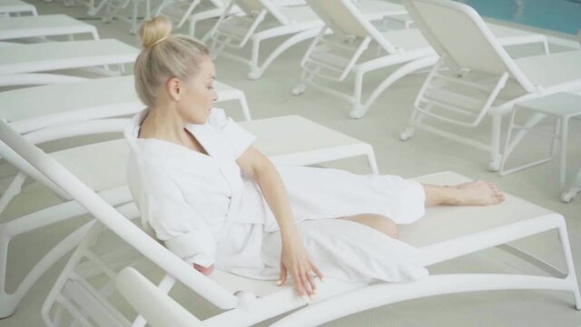 Armless woman resting on white deck chair in spa center