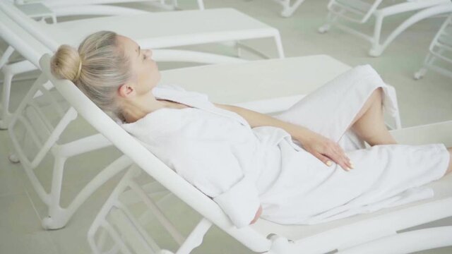 Woman with amputated hand lying on deck chair in spa center