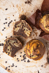 Soft and moist chocolate banana muffins with dark chocolate drops on grey rustic table. Homemade baked twisted cupcakes. Natural light, selective focus, copy space