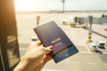 Orange suitcase with vaccine passport and face mask on it with airplane on background. airport tourist photo ready to travel after pandemic time. Vaccinated proof certificate 