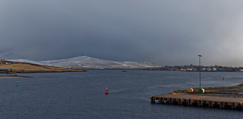 The lightly snow covered Mark of Bressay with its tall communication towers overlooking the town of Lerwick during a winters storm.