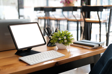 Front view of office desk with blank screen display of tablet in the cafe.