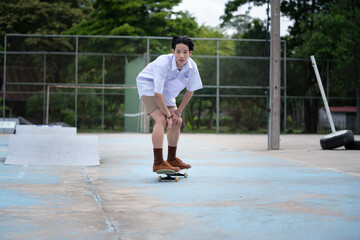 Teen Asian Skater boy in student uniform skating in the local skate park.