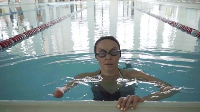 Slow motion of handless woman in goggles training in swimming pool