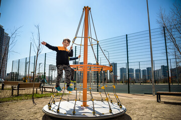 Two young boy active little child playing climbing at spring metal playground his hand to exercise at outdoor. Warm sunny day. Friendship concept